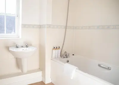 a white bathroom with a tub and a sink and a bath tub at 4x Bed Elegant Home with Parking in Ely
