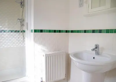 a white bathroom with a sink and a shower at 4x Bed Elegant Home with Parking in Ely
