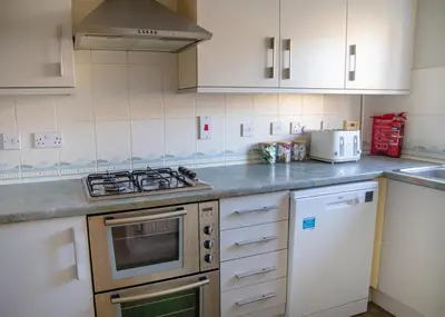a kitchen with white cabinets and a stove top oven at 4x Bed Elegant Home with Parking in Ely
