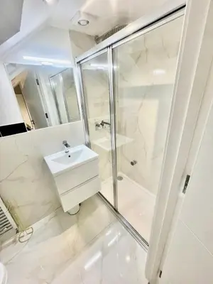 a white bathroom with a shower and a sink at cozy 1 bedroom flat near cambridge city centre in Milton