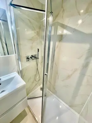 a shower with a glass door next to a sink at cozy 1 bedroom flat near cambridge city centre in Milton