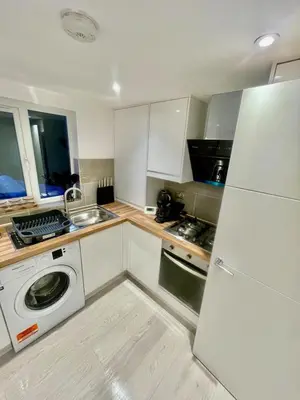 a kitchen with a washer and a white refrigerator at cozy 1 bedroom flat near cambridge city centre in Milton