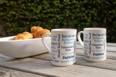 three coffee mugs sitting on a table with a plate of food at 8 Lee Road, Aldeburgh - Aldeburgh Coastal Cottages in Aldeburgh