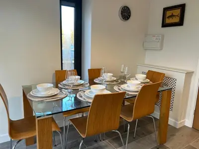 a dining room with a glass table and chairs at Mango Cottage in Thorndon