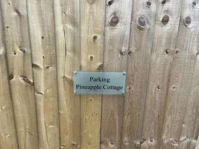a sign on the side of a wooden fence at Pineapple Cottage in Thorndon