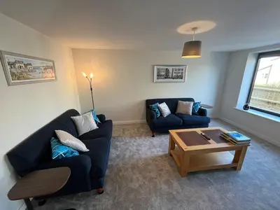 a living room with two blue couches and a coffee table at Pineapple Cottage in Thorndon