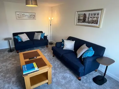 a living room with two blue couches and a coffee table at Pineapple Cottage in Thorndon