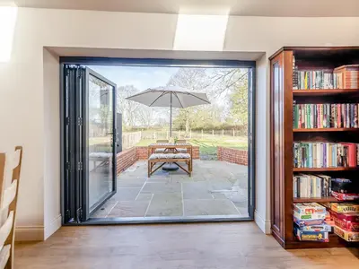 an open door to a patio with an umbrella at Maple Barn in Eye