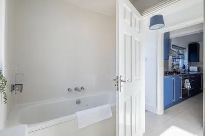 a white bathroom with a tub and a sink at Stylish 3-Bed Home in the Heart of the Cambridge in Cambridge