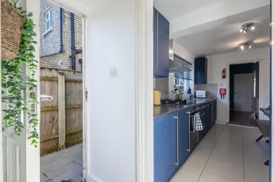 a kitchen with blue cabinets and a wooden fence at Stylish 3-Bed Home in the Heart of the Cambridge in Cambridge