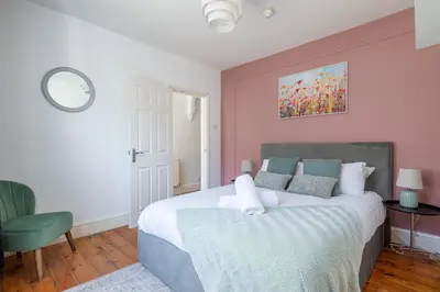 a bedroom with a large bed and a green chair at Stylish 3-Bed Home in the Heart of the Cambridge in Cambridge