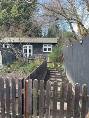 a fence in front of a house with a yard at Be Our Guest in Earls Colne