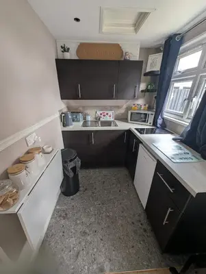 a small kitchen with white cabinets and a sink at Be Our Guest in Earls Colne