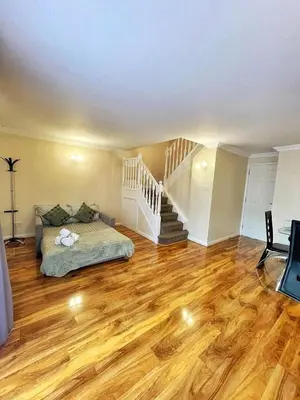 a living room with a bed and a staircase at Modern 3 Bed House In Essex By DLuxoria Short Lets & Serviced Accommodation With Pet Friendly, Free WiFi & Free Parking in Basildon