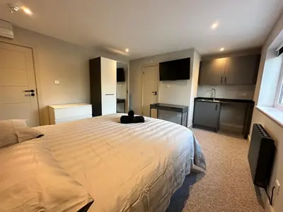a bedroom with a large bed and a kitchen at Captivating 7 -Bed House in Waltham Abbey in Waltham Abbey