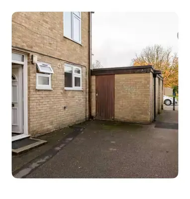 a brick house with a garage and a building at Nice and spacious room in Chesterton