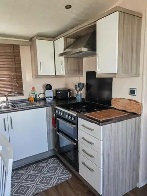 a kitchen with white cabinets and a stove top oven at Green House Moselle in Jaywick Sands