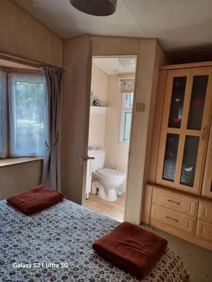 a bedroom with a bed and a bathroom with a toilet at The Fox - Free Fishing, pets welcome - static caravan in Clare, Suffolk in Clare