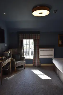 a bedroom with a bed and a desk and a window at Elveden Inn in Elveden