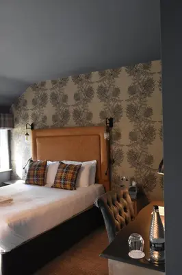 a bedroom with a bed and a wall with wallpaper at Elveden Inn in Elveden