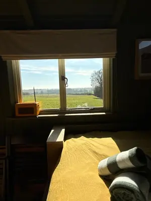 a bedroom with a window with a view of a field at 'Russet' Hut on fruit farm in Charsfield