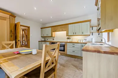 a kitchen with white cabinets and a wooden table at Finest Retreats - The House at No 47 in West Wickham