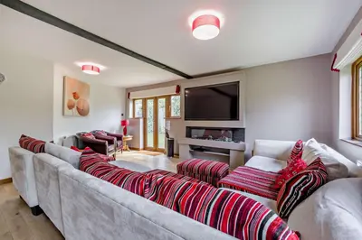 a living room with a long couch with red pillows at Finest Retreats - The House at No 47 in West Wickham