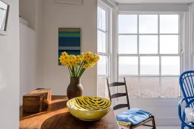 a dining room with a table with a vase of flowers at Art Cottage, Aldeburgh in Aldeburgh