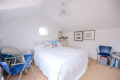 a bedroom with a white bed and two blue chairs at Art Cottage, Aldeburgh in Aldeburgh