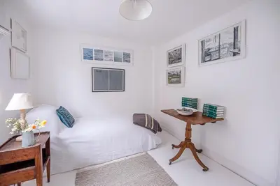 a white room with a bed and a table at Art Cottage, Aldeburgh in Aldeburgh