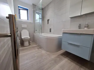 a bathroom with a tub and a toilet and a sink at Modern Cambridge Flat-Easy A14 Access and City Links in Milton