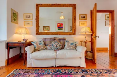 a living room with a white couch and a mirror at Pass the Keys Charming Cottage in the City Centre Free Parking in Cambridge