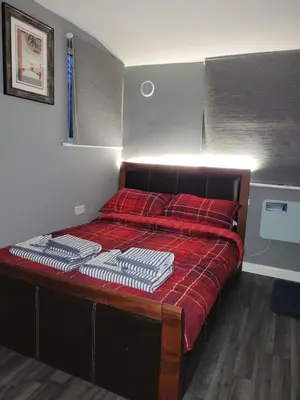 a bedroom with a bed with red sheets and a red blanket at The Nook in Great Cornard