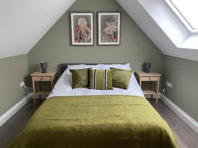 a bedroom with a bed with a green blanket at Primrose Lodge in Maldon in Maldon