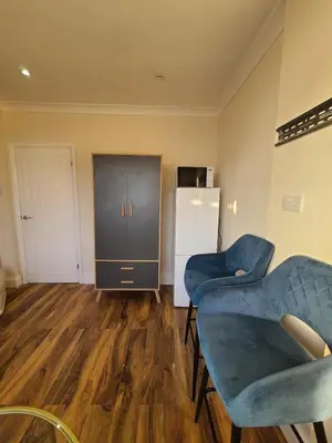 a living room with two chairs and a refrigerator at One Bed and Bath in Rochford in Rochford