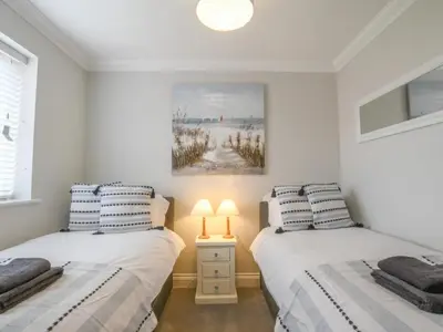 two beds in a white room with a picture on the wall at 51 Halesworth in Holton