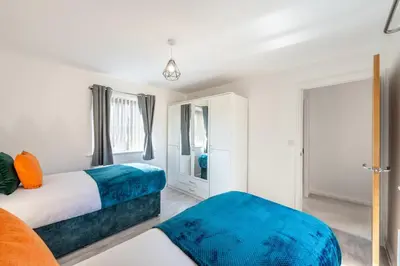 a bedroom with two beds and a mirror at Cambridge 5 Bedrooms Sleeps 10 Free Parking 4 Bathrooms in Long Stanton