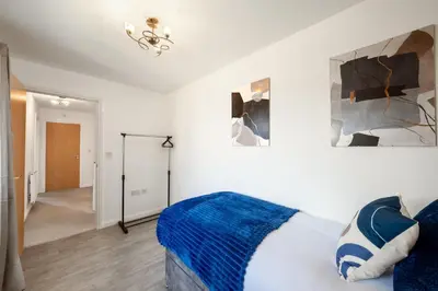 a bedroom with a bed with a blue blanket at Cambridge 5 Bedrooms Sleeps 10 Free Parking 4 Bathrooms in Long Stanton