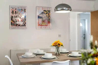 a dining room with a table with chairs and flowers at Cambridge 5 Bedrooms Sleeps 10 Free Parking 4 Bathrooms in Long Stanton