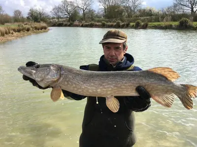 a man holding a large fish in the water at Fushia Chalet a lovely little rural retreat in Saxtead