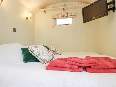 a bed with two towels sitting on top of it at Woodlands Retreat Shepherd's Hut in Woodbridge