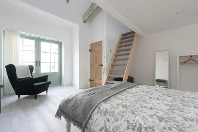 a bedroom with a bed and a chair and a staircase at Historic Old Stables in Bishops Stortford