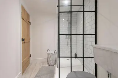 a white bathroom with a glass shower backdoor at Historic Old Stables in Bishops Stortford