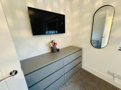 a bathroom with a dresser with a mirror and a tv at Cozy Modern Home Basildon Long stay Contractors Sleeps 6 in Basildon