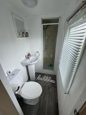 a white bathroom with a toilet and a sink at Seawick Holiday Park Caravan Hire in Saint Osyth