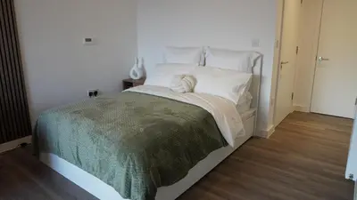 a white bed with a green blanket and white pillows at Cambridge Urban Suite in Cambridge