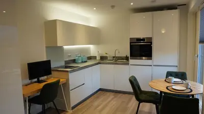 a kitchen with white cabinets and a table with chairs at Cambridge Urban Suite in Cambridge