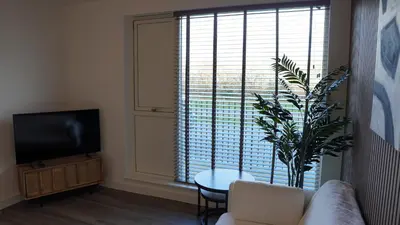 a living room with a couch and a large window at Cambridge Urban Suite in Cambridge