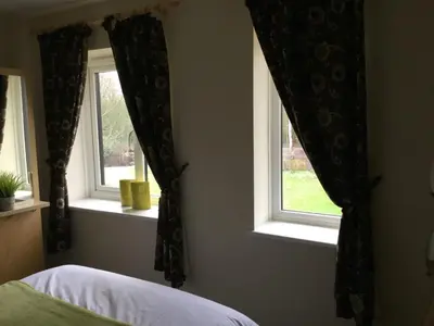a bedroom with two windows with black curtains at The Old Grain Store Bed & Breakfast in Pidley