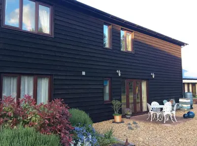 a black house with tables and chairs in front of it at The Old Grain Store Bed & Breakfast in Pidley